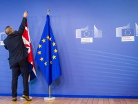 An EU official hangs the Union Jack next to the European Union flag at the VIP entrance at the European Commission headquarters in Brussels on Tuesday, Feb. 16, 2016. British Prime Minister David Cameron is visiting EU leaders two days ahead of a crucial EU summit.  (AP Photo/Geert Vanden Wijngaert)