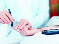 An elderly woman receiving an injection in her finger to check her blood sugar levels